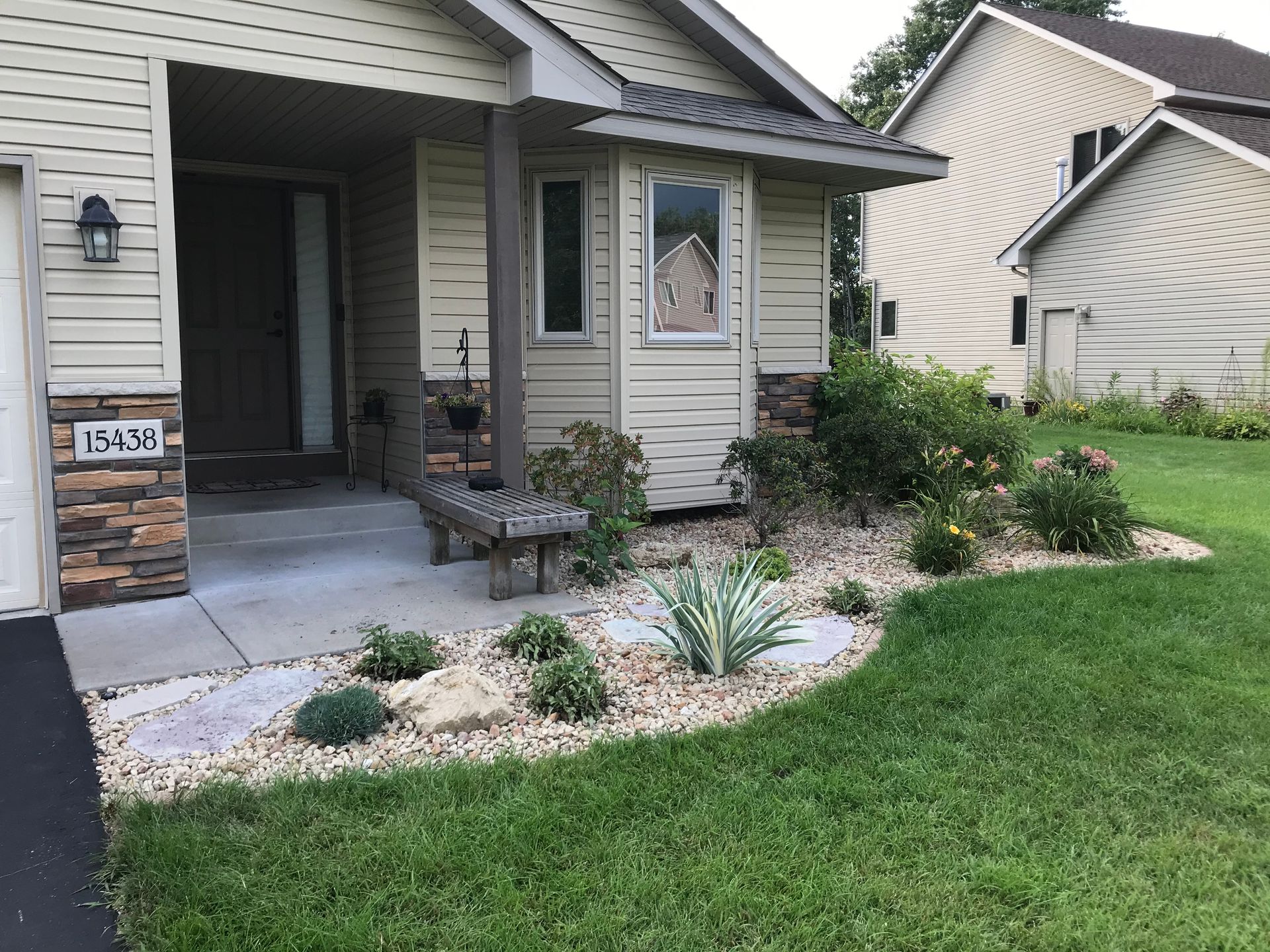 A house with rock garden with plants in front of it.