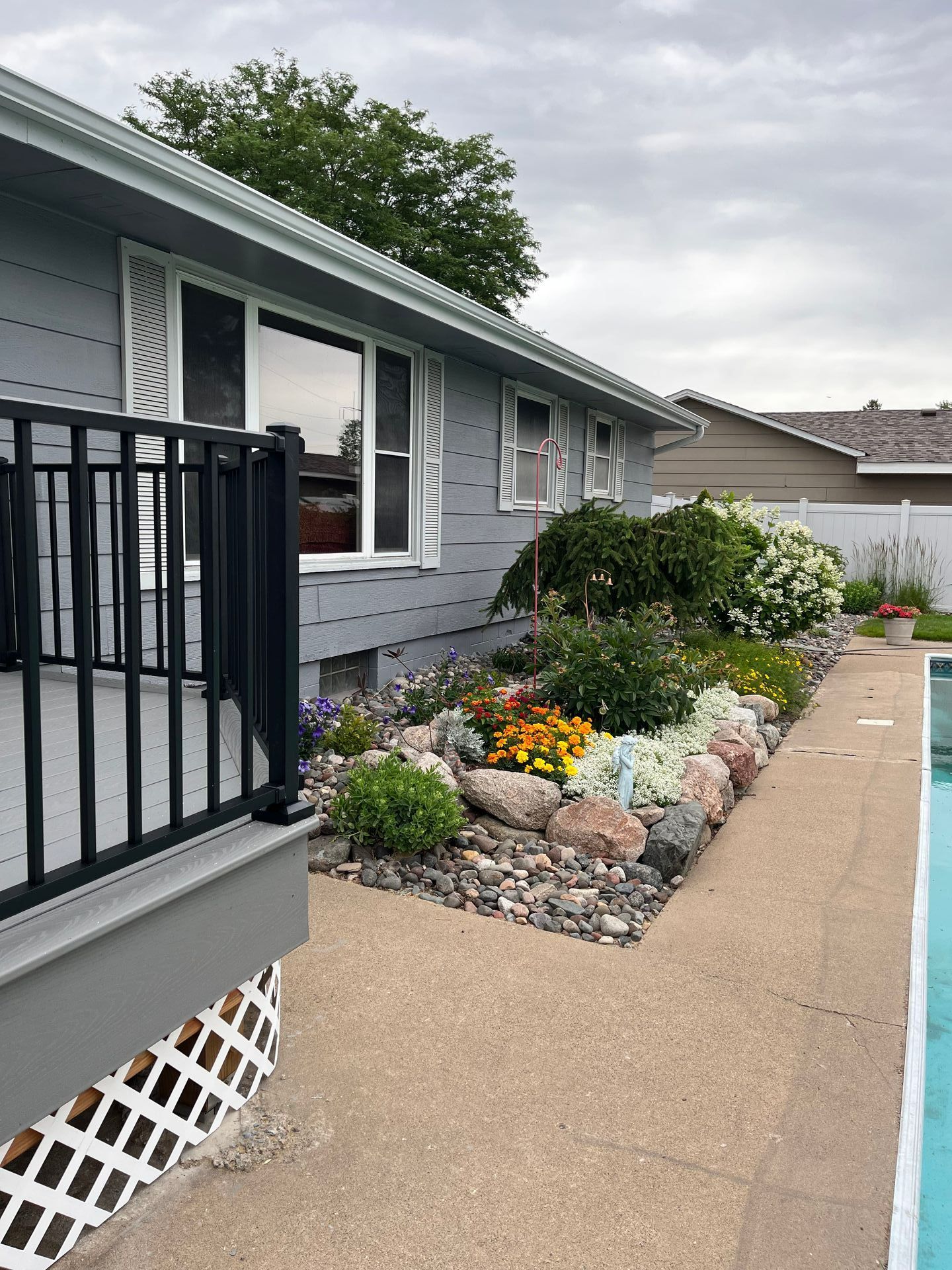 A house with a rock garden with many plants in front of it.