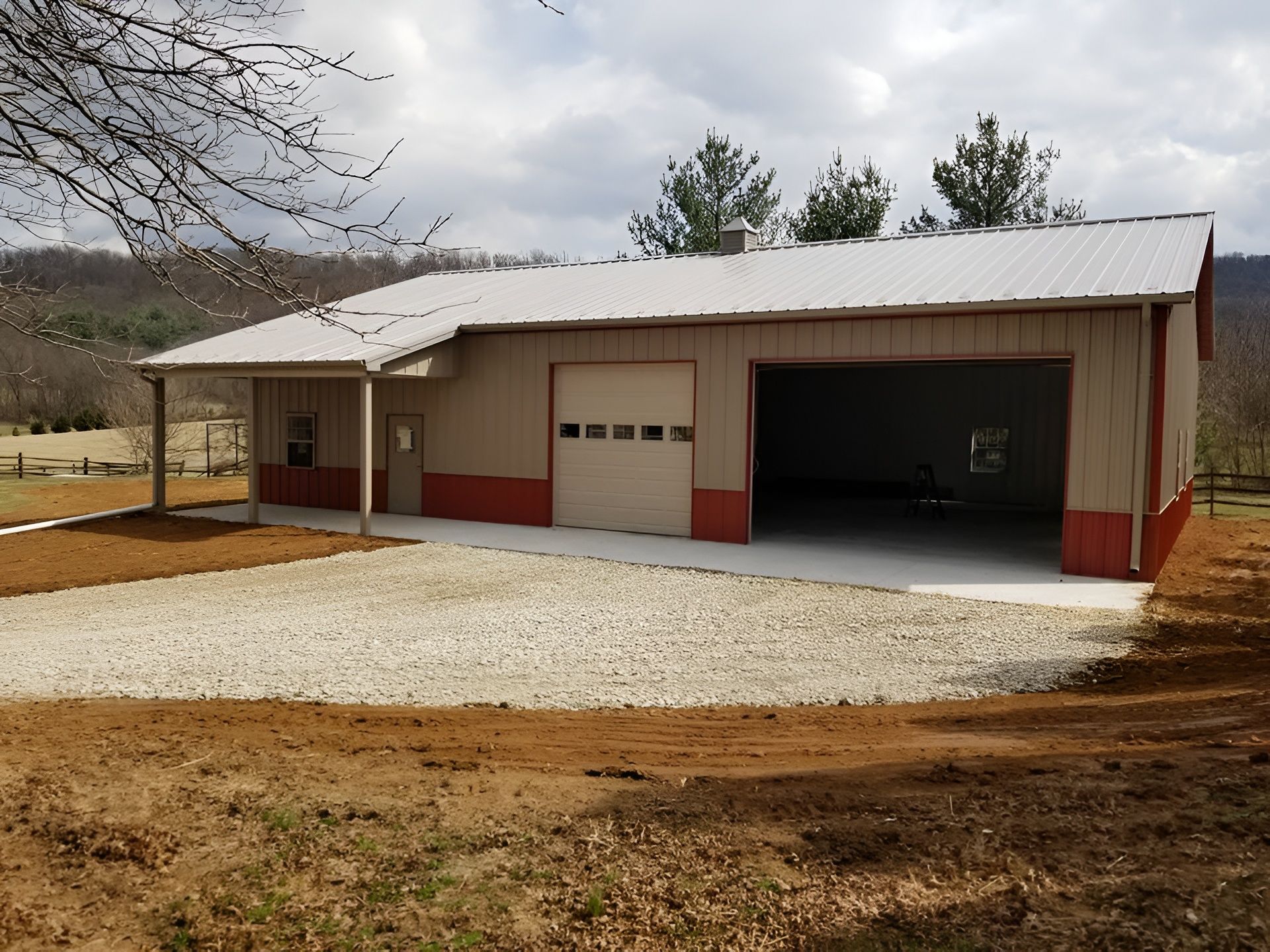 A metal pole barn with beige siding, a red base, a white roof, a closed garage door, and an open equipment bay.