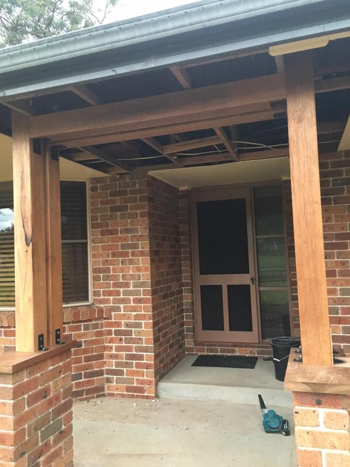 A Brick House With a Screen Door and a Wooden Porch — LVL Constructions in Newcastle, NSW