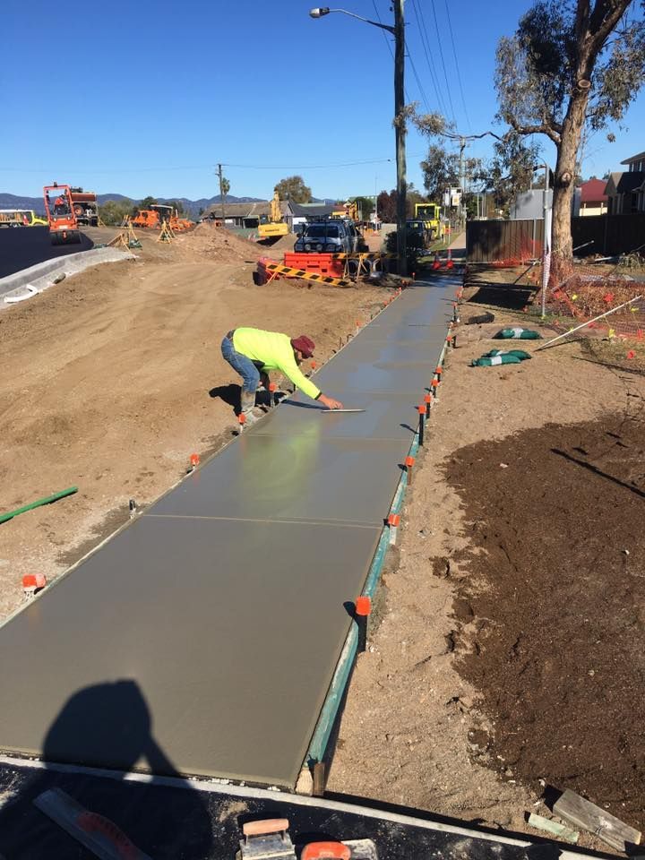 A Construction Worker is Laying Concrete on a Sidewalk — LVL Constructions in Newcastle, NSW