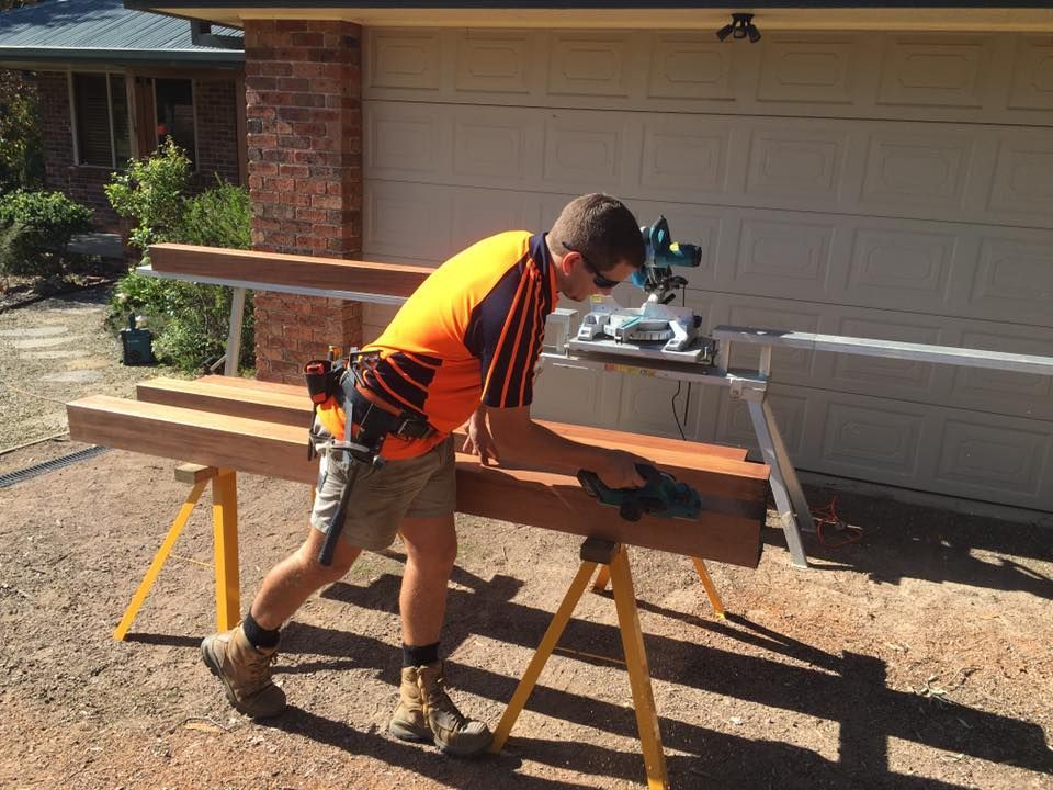 A Man is Cutting a Piece of Wood With a Saw — LVL Constructions in Newcastle, NSW
