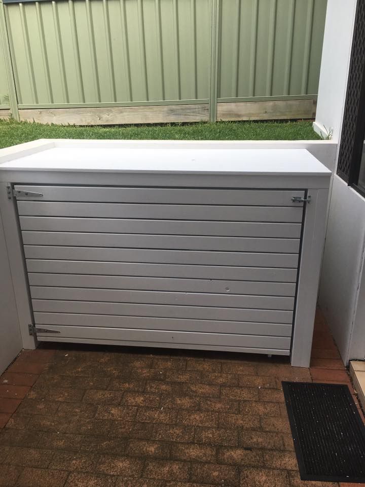 A White Wooden Box is Sitting on a Brick Patio Next to a Fence — LVL Constructions in Newcastle, NSW