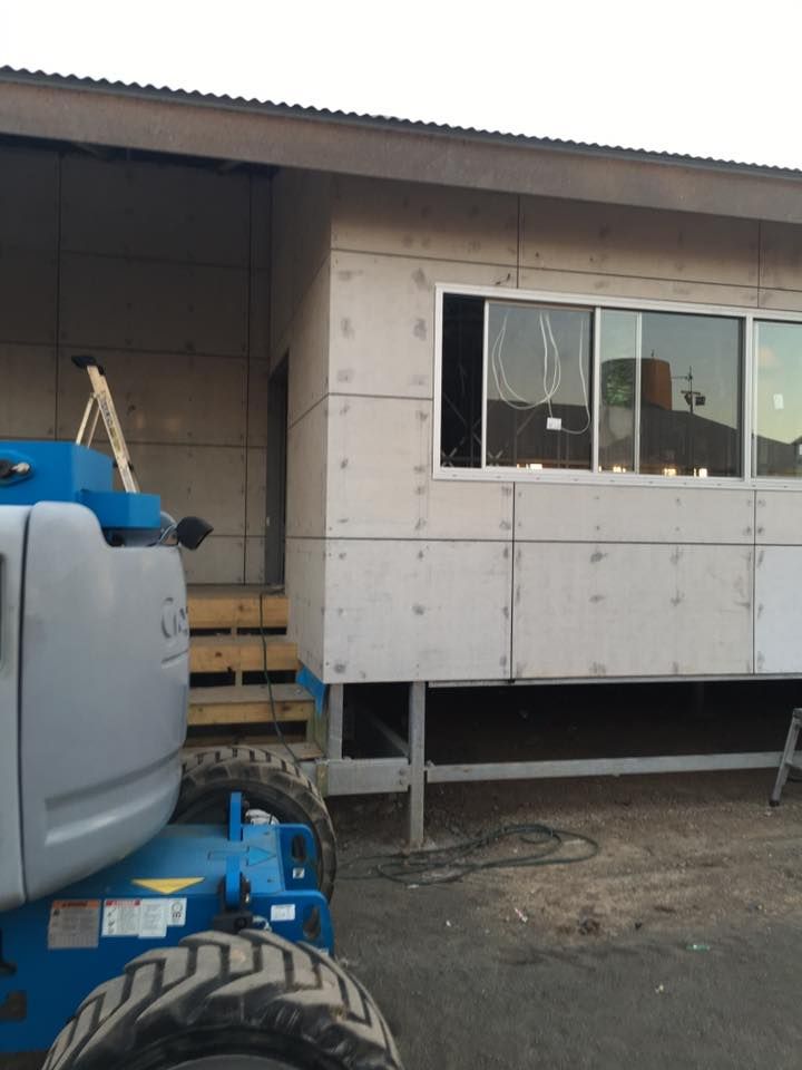 A Blue Tractor is Parked in Front of a White Building — LVL Constructions in Newcastle, NSW