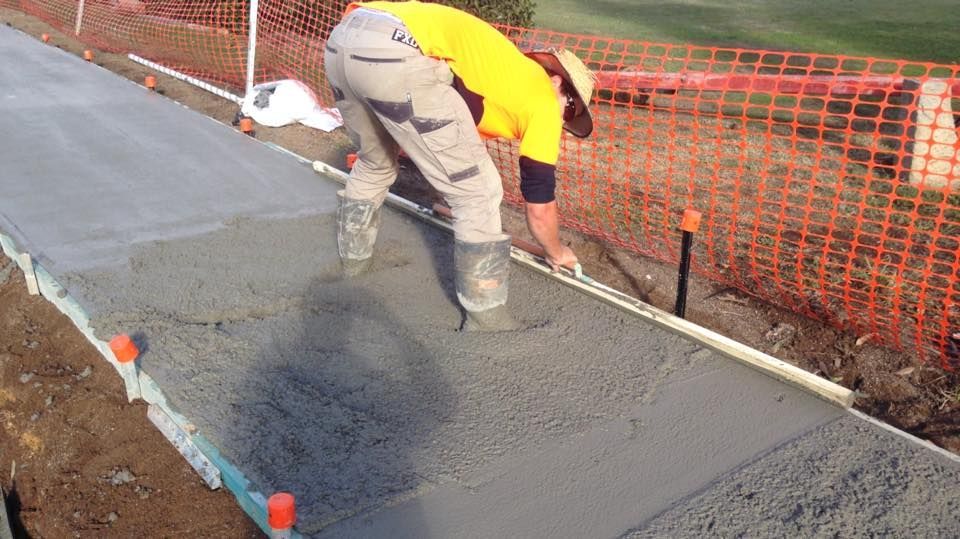 A Man is Laying Concrete on a Sidewalk — LVL Constructions in Newcastle, NSW