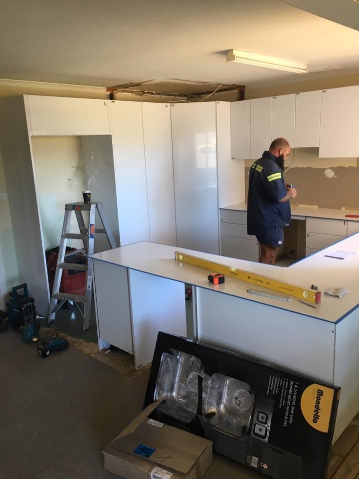 A Man is Standing in a Kitchen Measuring a Counter Top — LVL Constructions in Newcastle, NSW