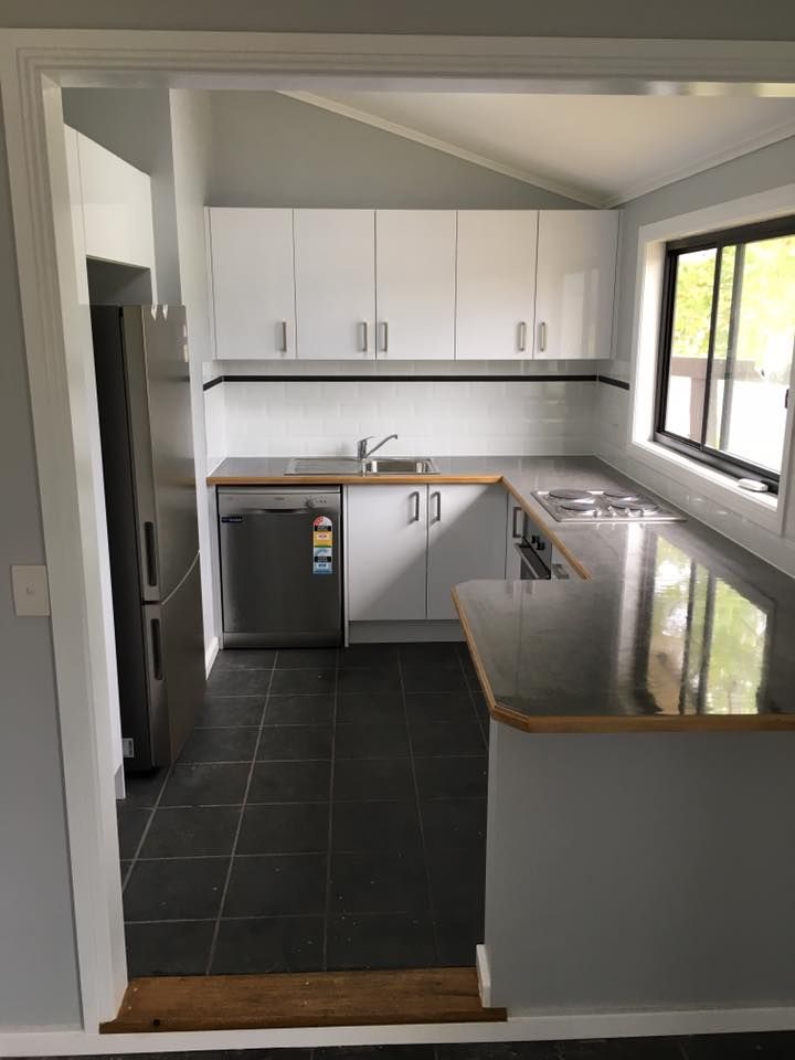 A Kitchen With White Cabinets and Stainless Steel Appliances — LVL Constructions in Newcastle, NSW