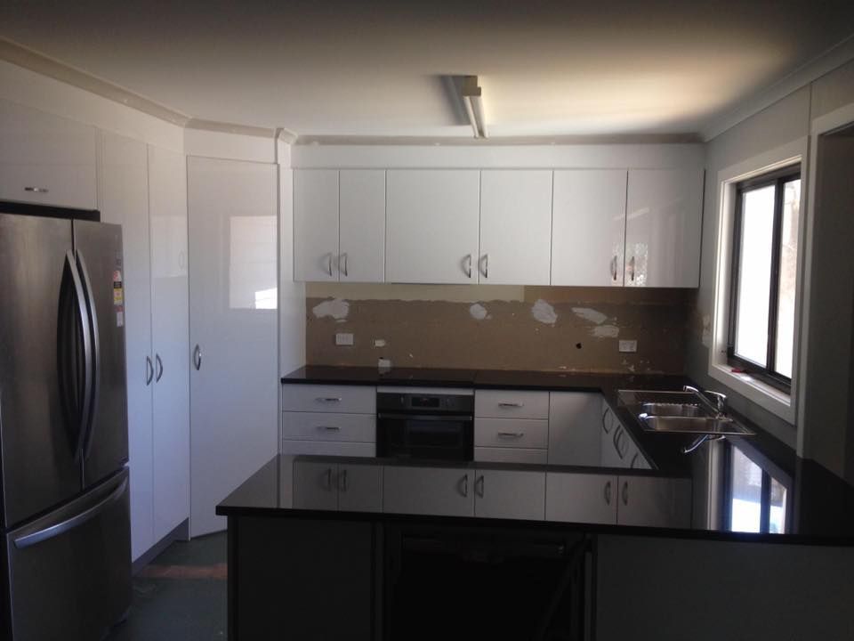 A Kitchen With White Cabinets and Black Counter Tops — LVL Constructions in Newcastle, NSW