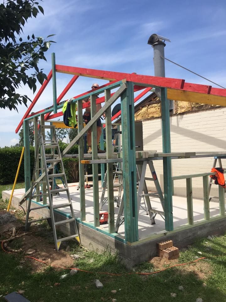 A Man is Standing on a Ladder in Front of a Building Under Construction — LVL Constructions in Newcastle, NSW