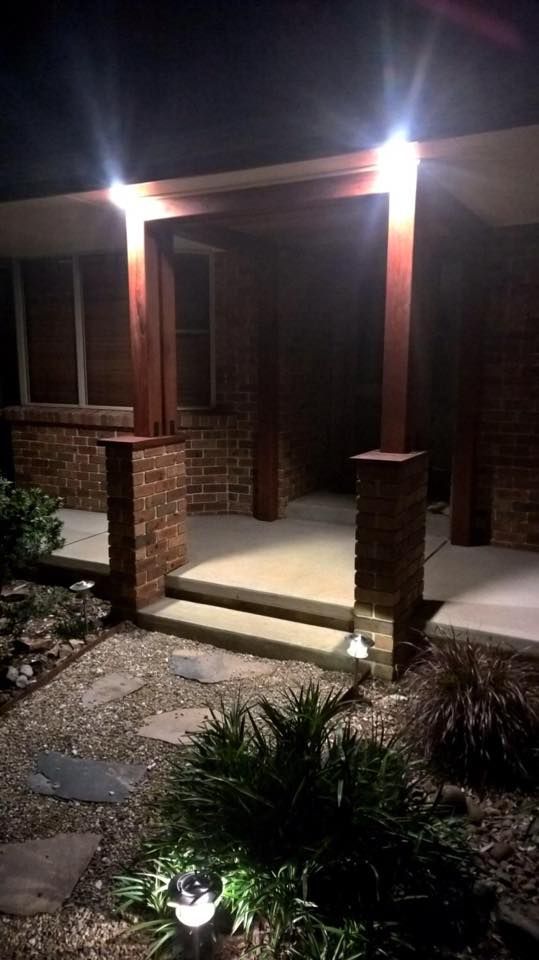 The Front Porch of a Brick House is Lit Up at Night — LVL Constructions in Newcastle, NSW