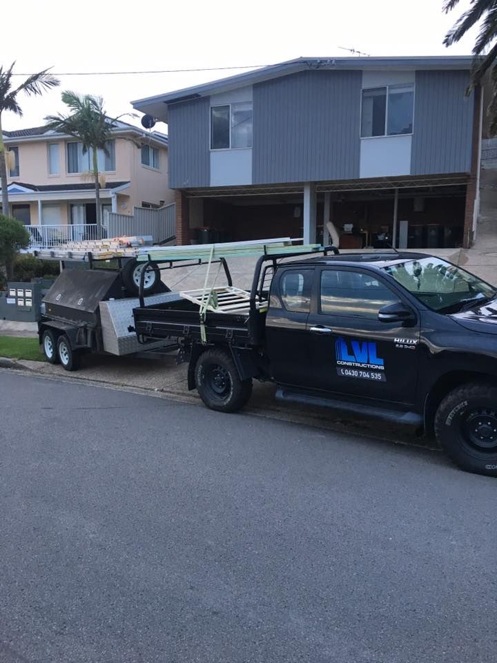 A Truck With a Trailer Attached to It is Parked in Front of a House — LVL Constructions in Newcastle, NSW