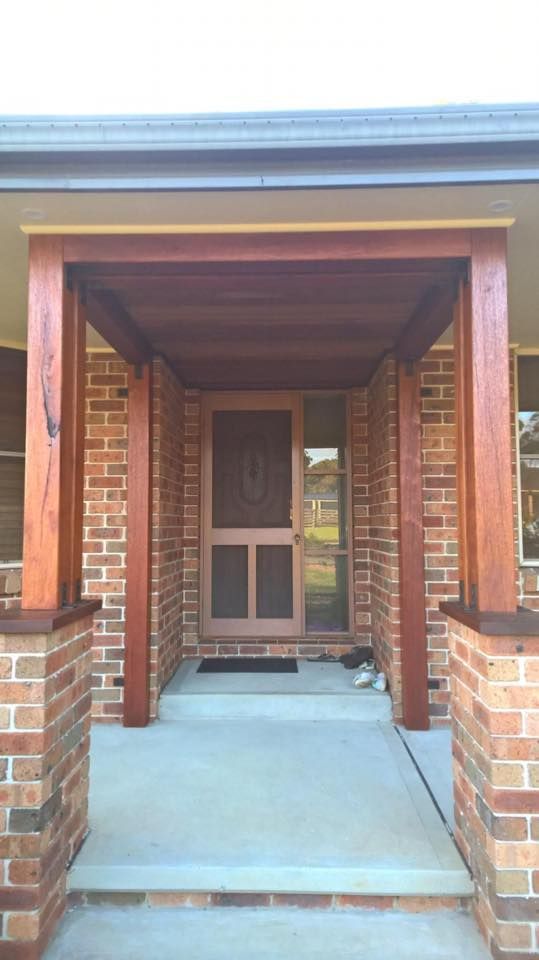 A Brick House With a Screen Door and a Wooden Porch — LVL Constructions in Newcastle, NSW