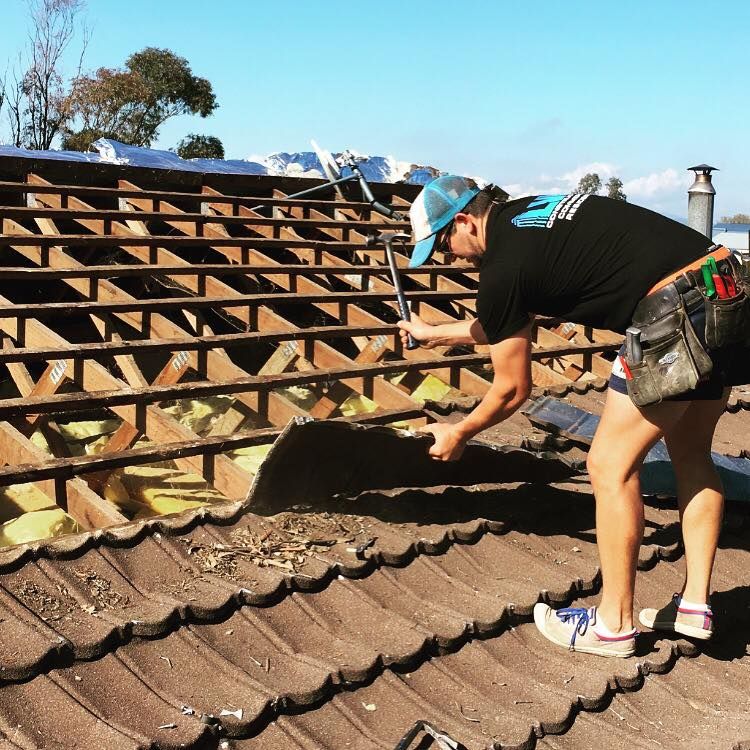 A Man is Working on a Roof With a Hammer — LVL Constructions in Newcastle, NSW