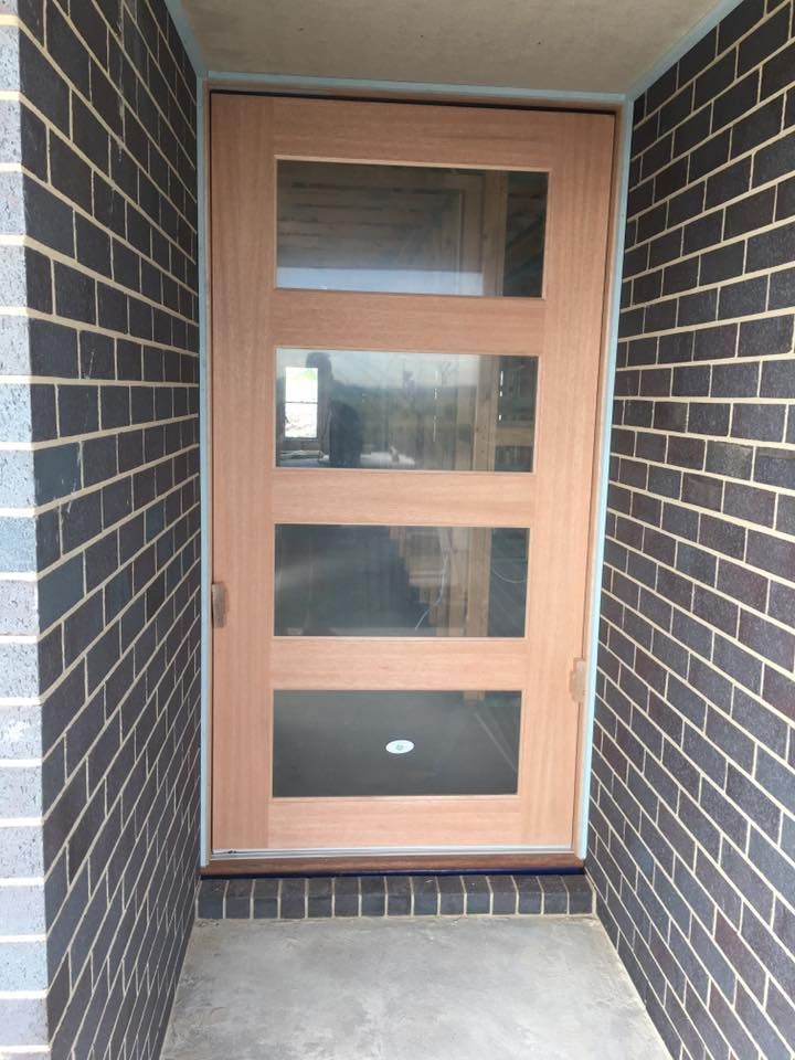 A Brick Wall With a Wooden Door in the Middle — LVL Constructions in Newcastle, NSW