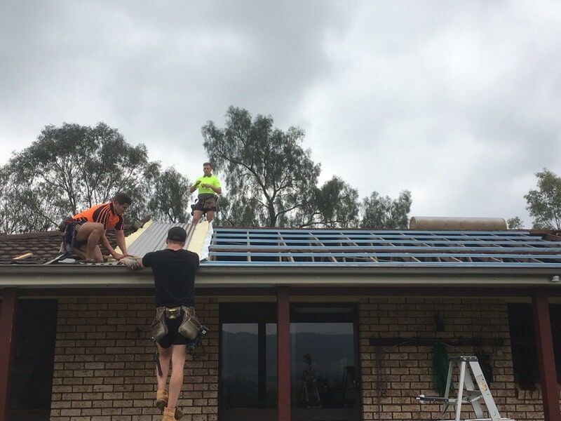 A Group of Men Are Working on the Roof of a Brick House — LVL Constructions in Newcastle, NSW