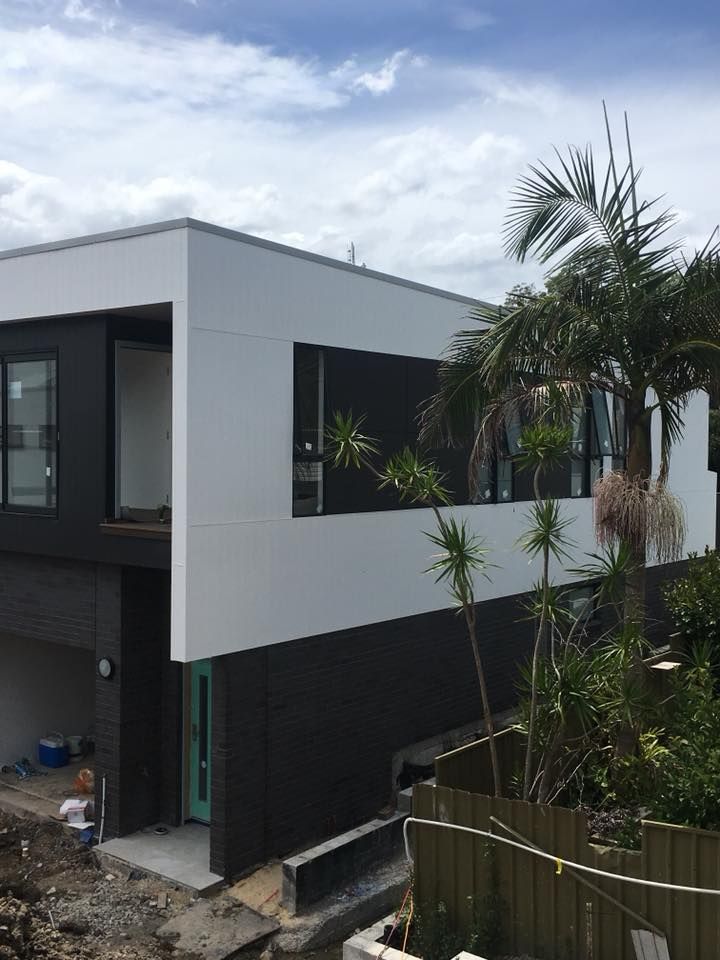 A Large White and Black House With a Palm Tree in Front of It — LVL Constructions in Newcastle, NSW