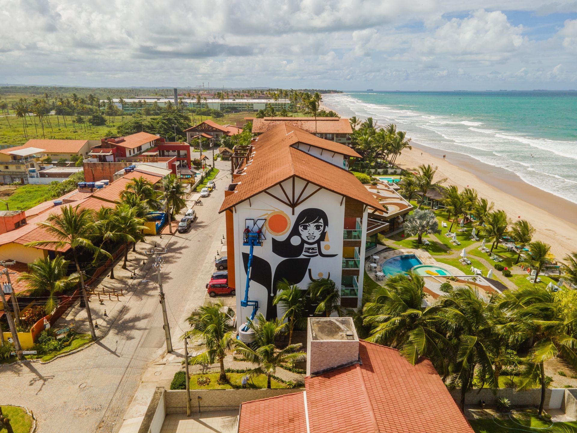 Vista aérea do hotel beira-mar em Porto de Galinhas, com piscina, coqueiros e acesso direto à praia