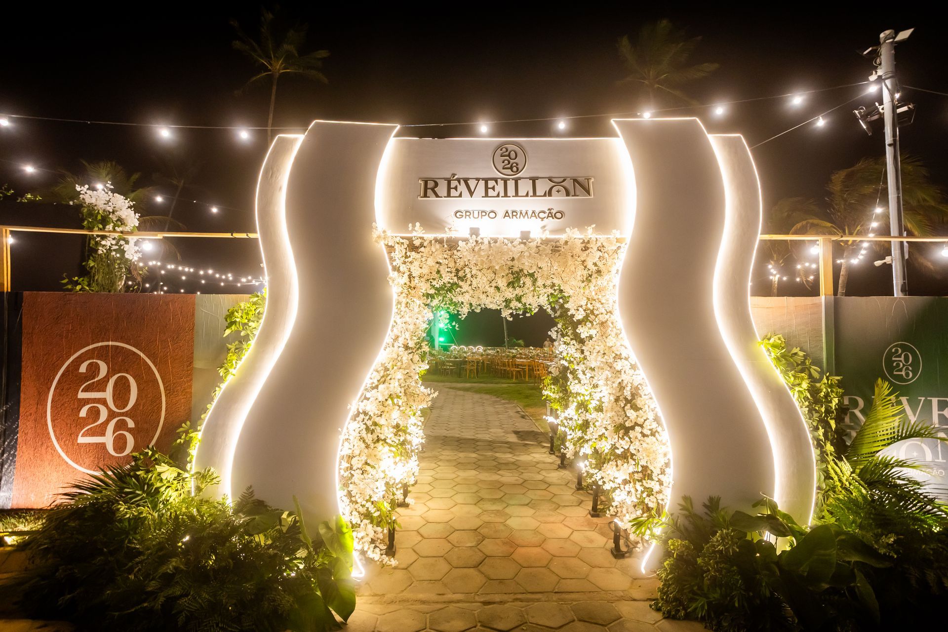 Entrada do Réveillon do Grupo Armação recebe os convidados com decoração iluminada à beira-mar.