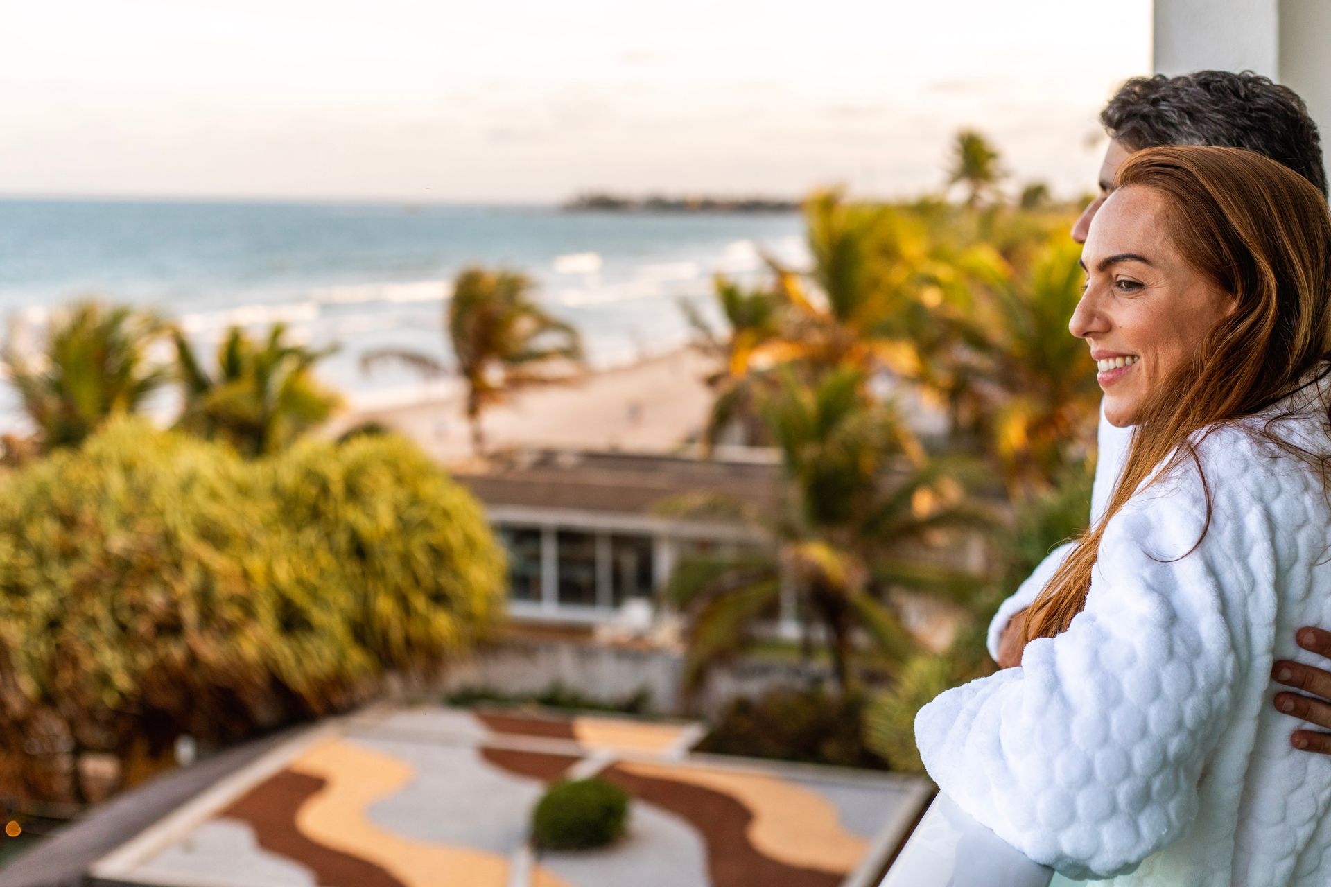 pessoas sentadas assistindo música ao vivo em área externa à noite com palco, coqueiros e iluminação decorativa