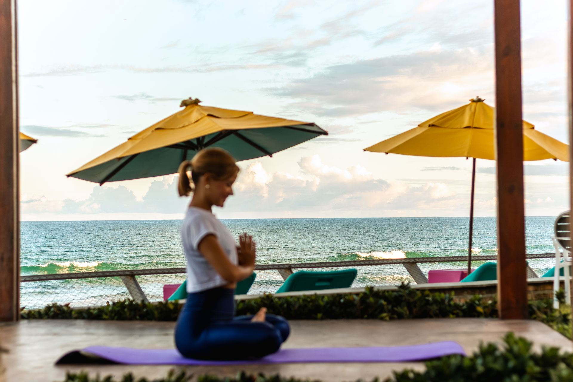 Pessoa pratica yoga com vista para o mar em um espaço ao ar livre durante o amanhecer.