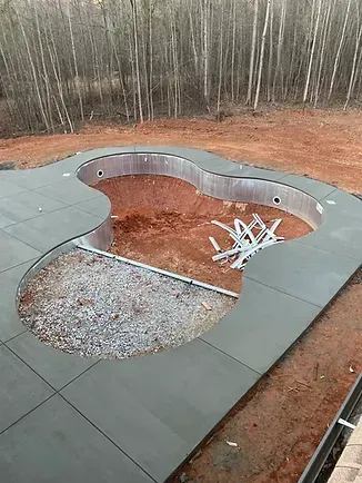 In the middle of a dirt field, a swimming pool is being built.