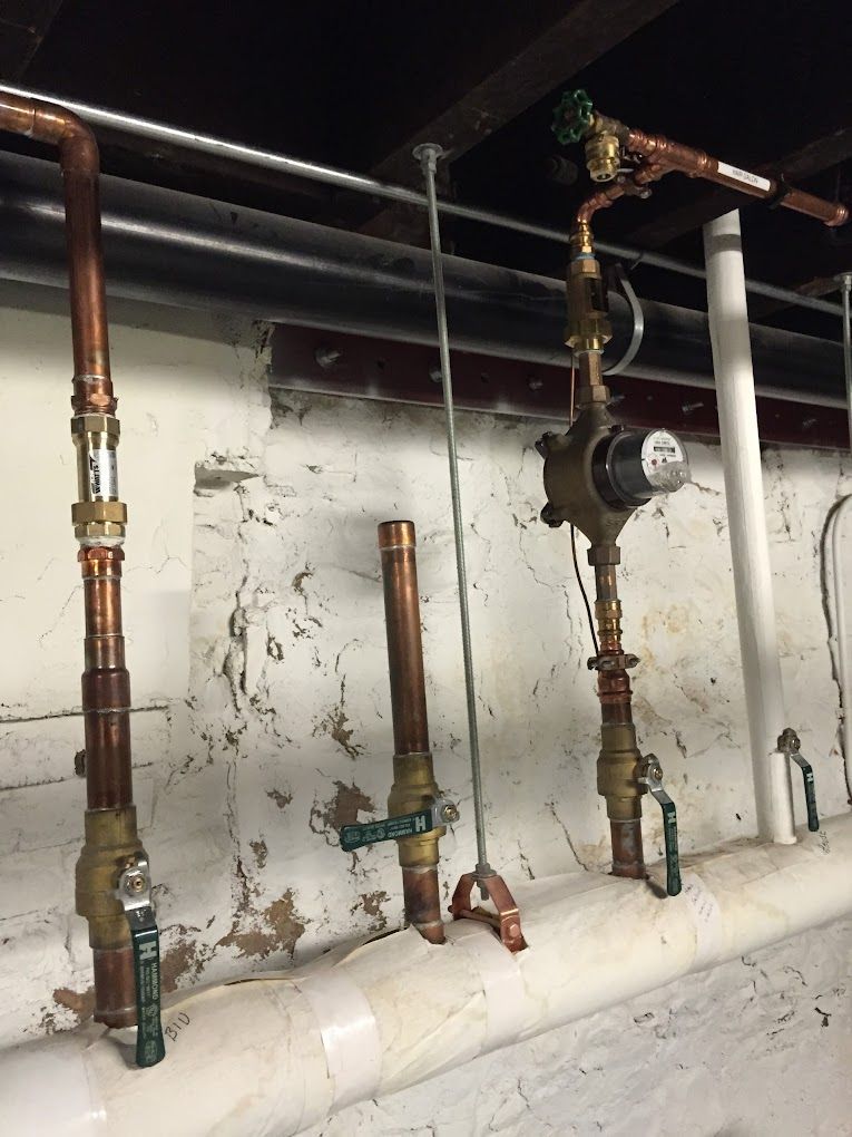 A row of copper pipes and valves hanging from a wall.