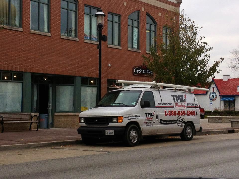 A white van is parked in front of a brick buildingTM