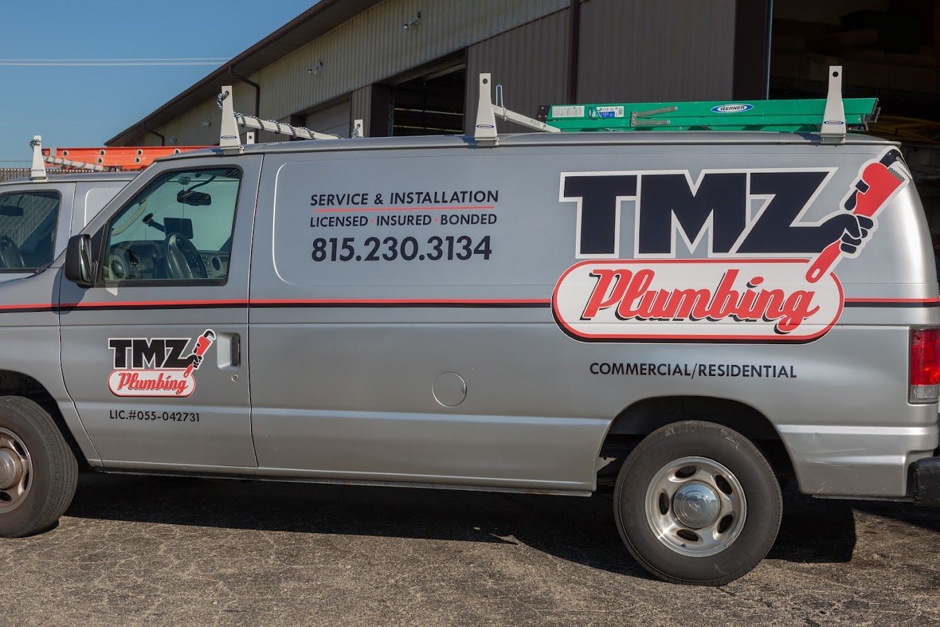 A tmz plumbing van is parked in front of a building