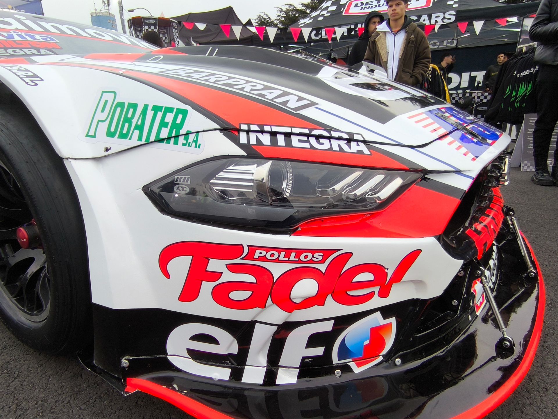 Coche de carreras blanco, rojo y negro con logotipos de patrocinadores en la parte delantera
