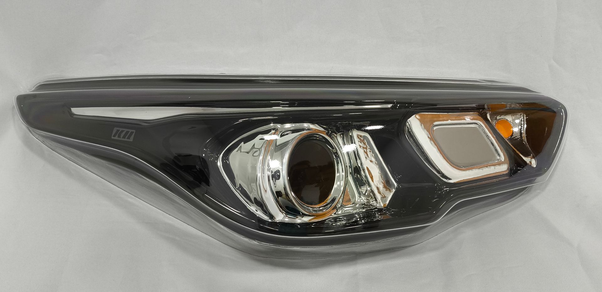 Conjunto de faro delantero para automóvil con moldura cromada y carcasa negra.