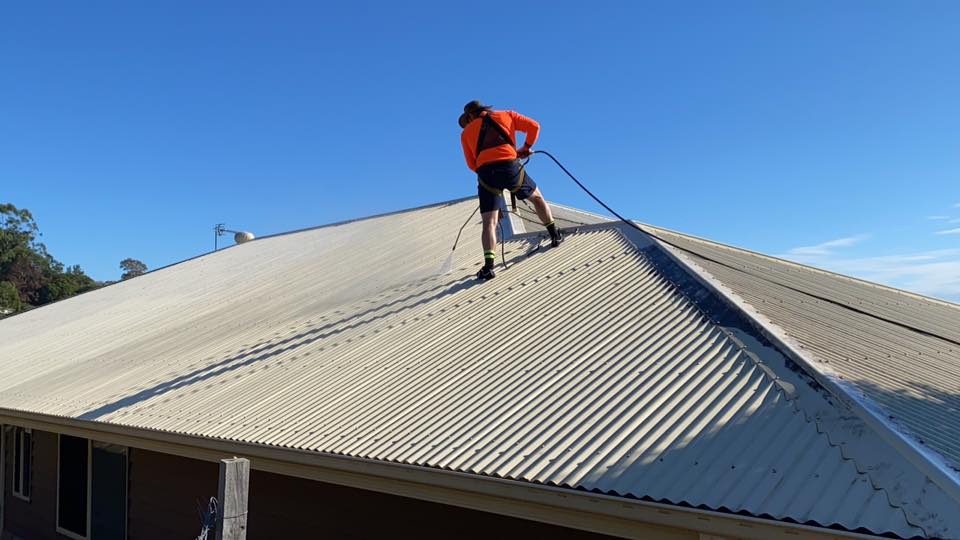 Man Cleaning the Roof using Pressure Cleaner — Crossy’s Roof Restorations Pty Ltd in Lismore Heights, NSW