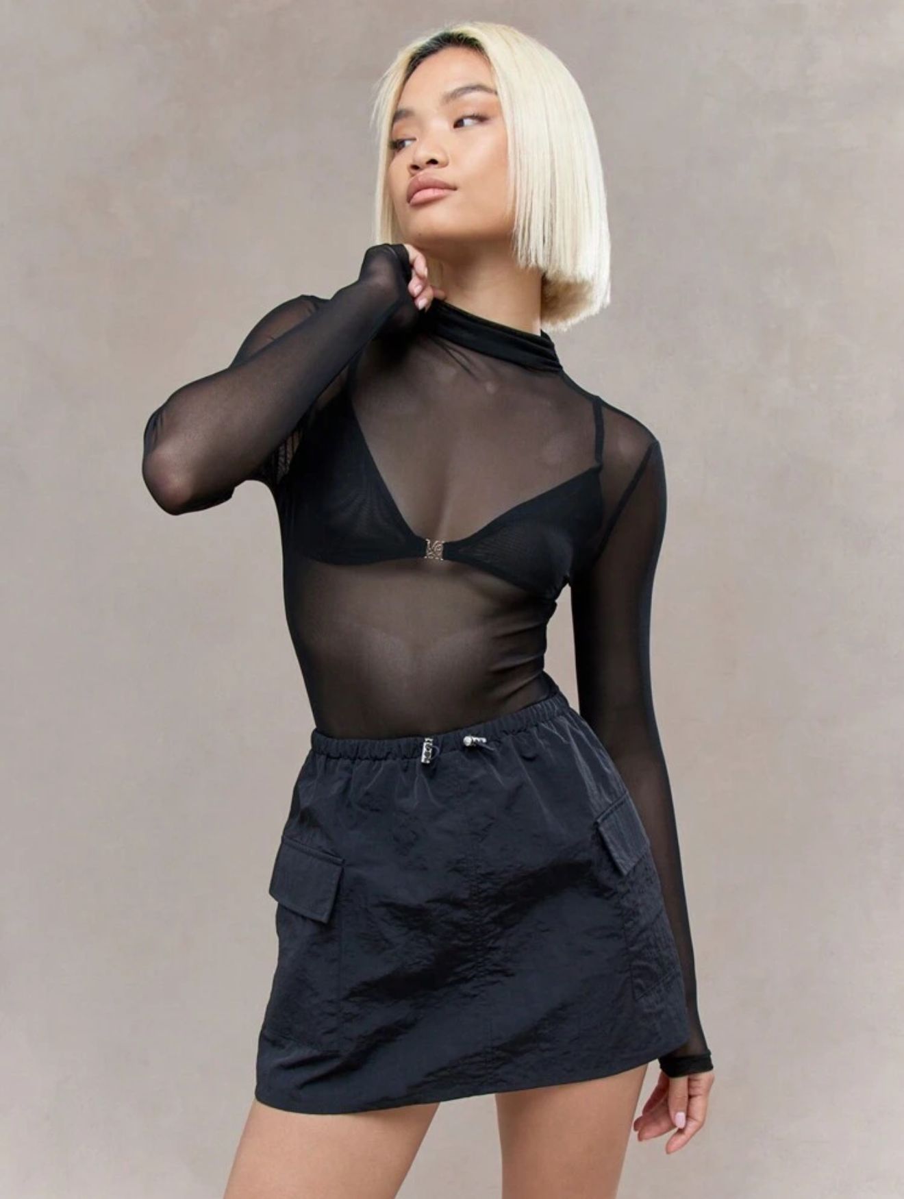 Una mujer lleva una blusa negra transparente y una falda negra.