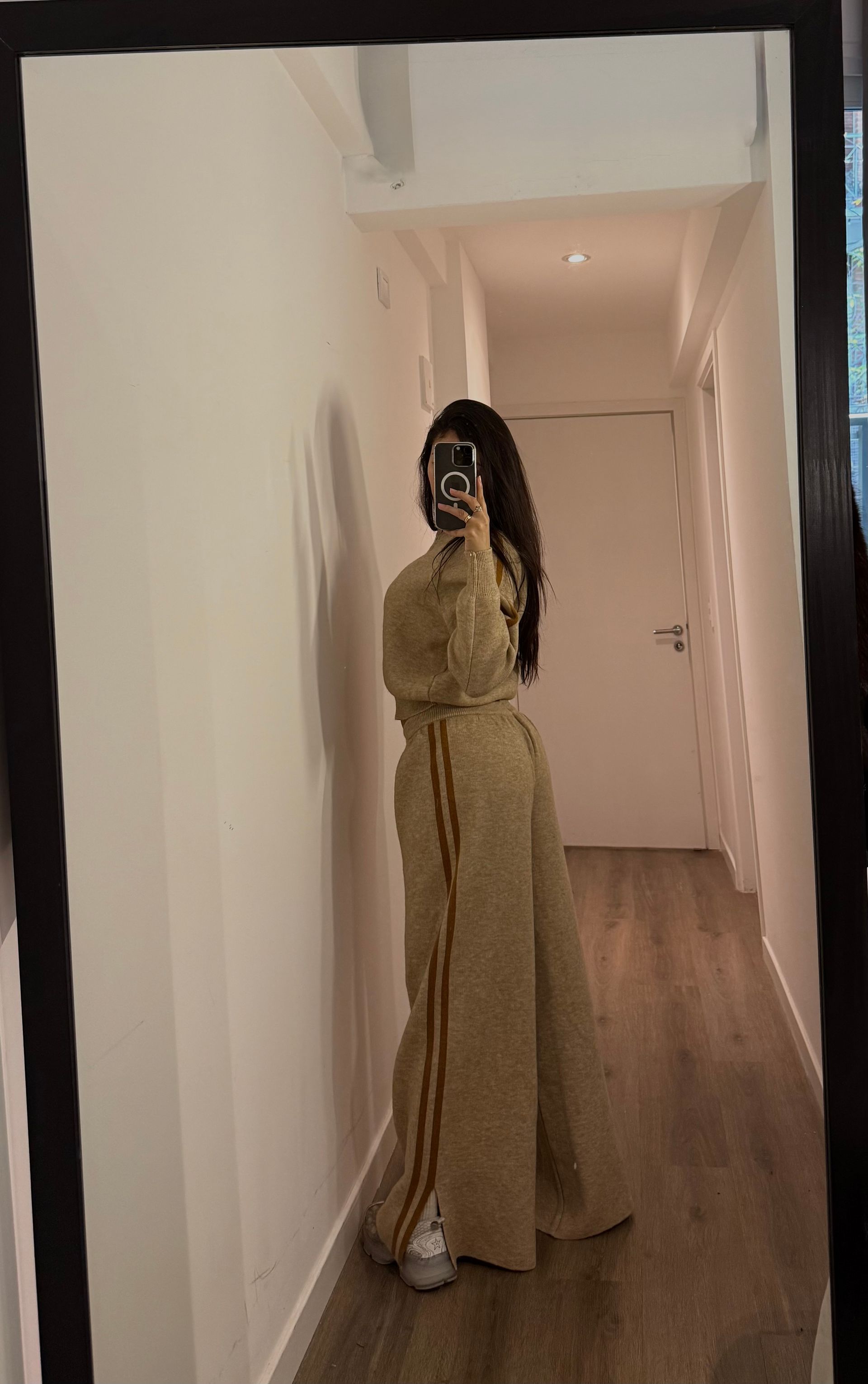 Conjunto de punto beige con rayas doradas, compuesto por chaqueta con cremallera y pantalón a juego, colgado en perchero.