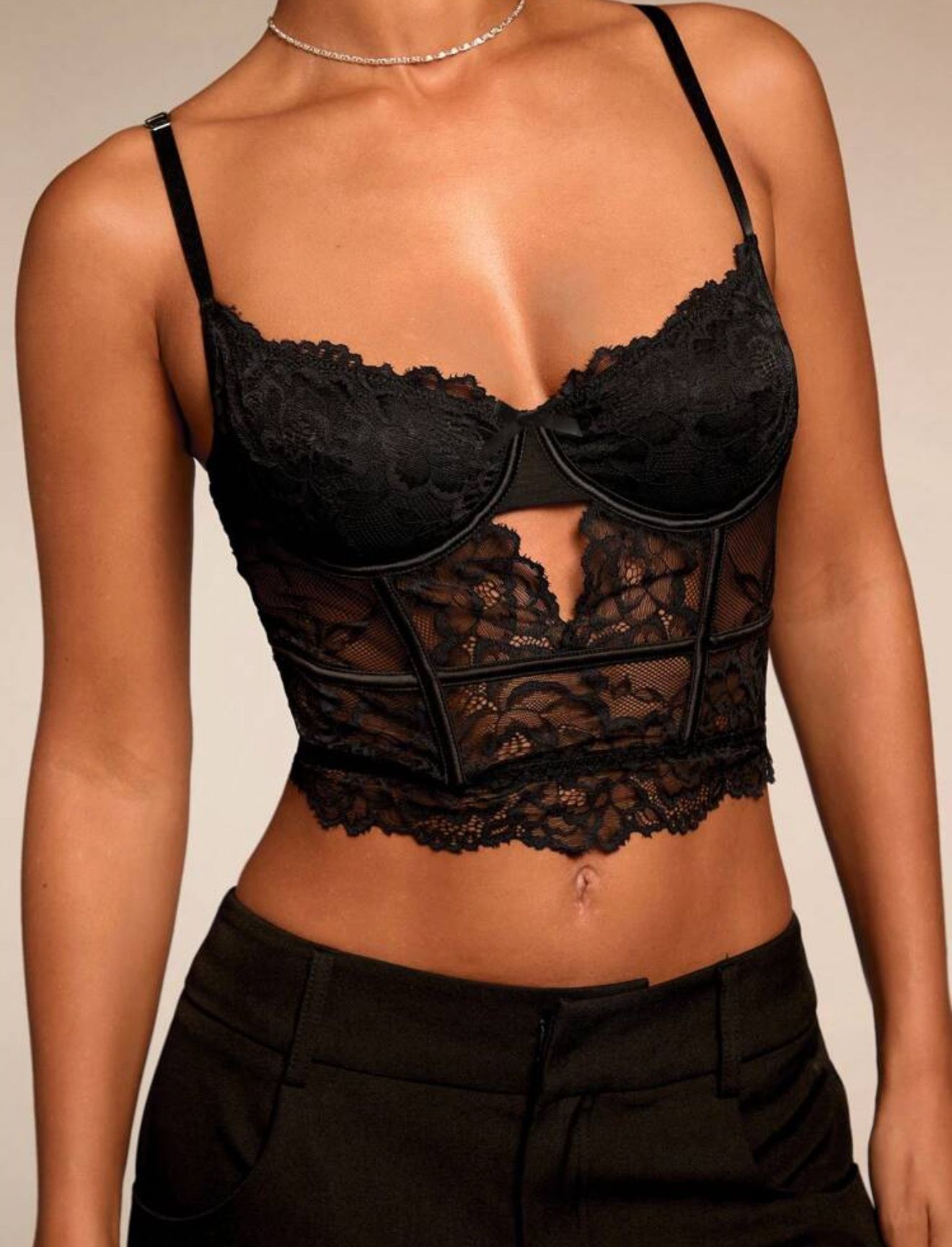 Mujer con traje pantalón negro y top de encaje, sosteniendo un bolso rojo.