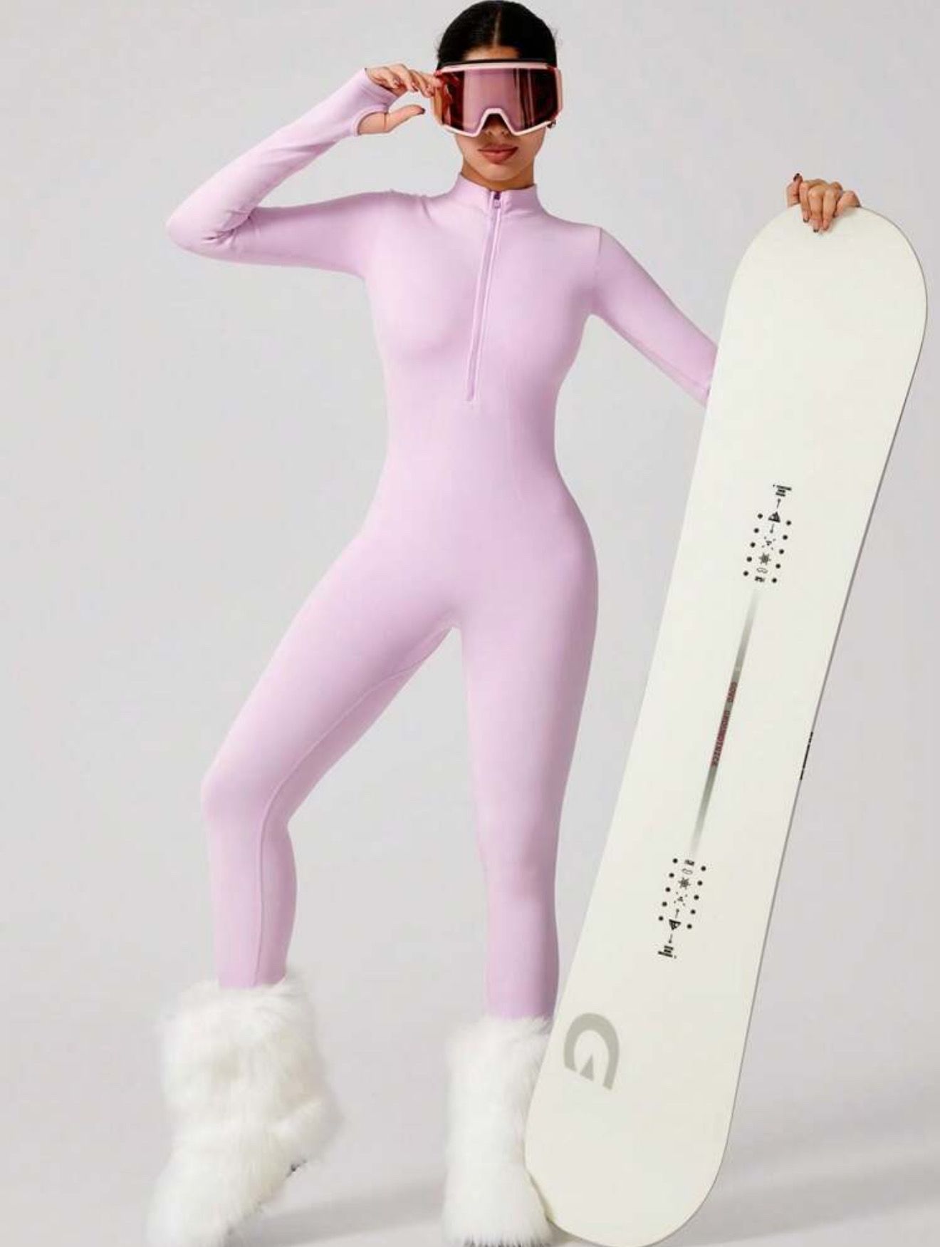 Mujer con mono rosa con tabla de snowboard y gafas en un entorno nevado.