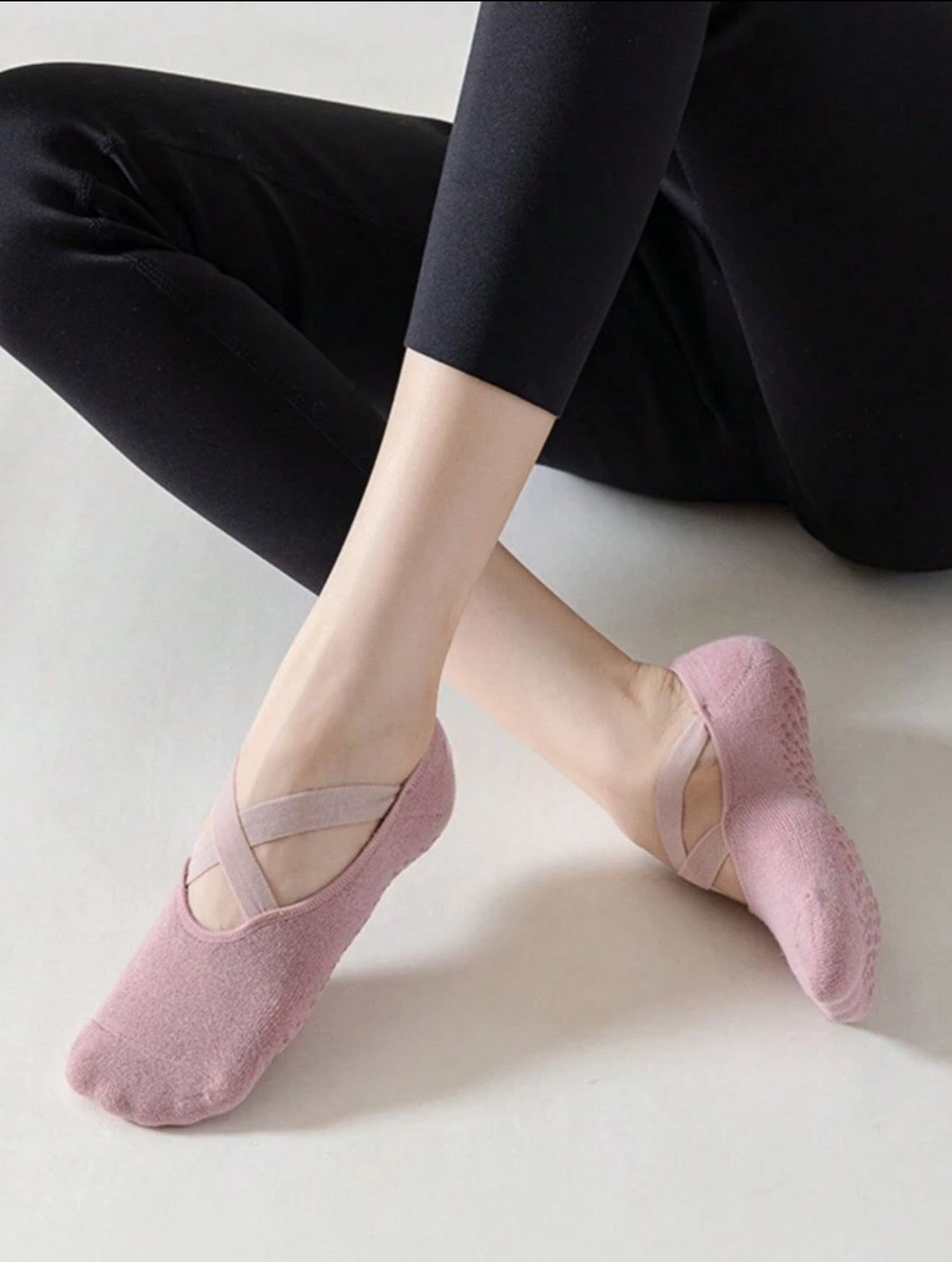 Calcetines de yoga negros con tiras cruzadas en los pies, leggings negros.