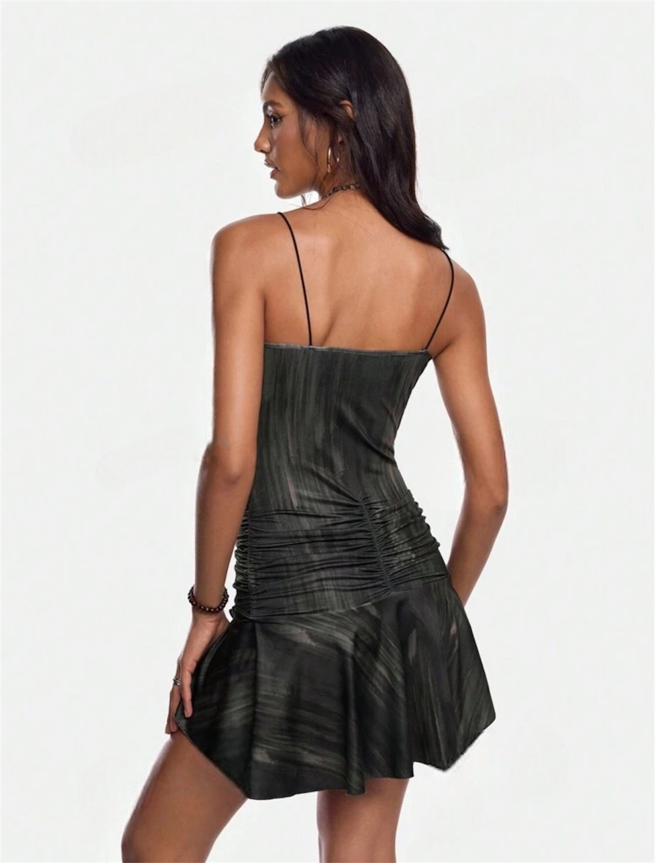 Mujer con vestido negro, pecho abierto, volantes en la falda, joyas, fondo neutro.