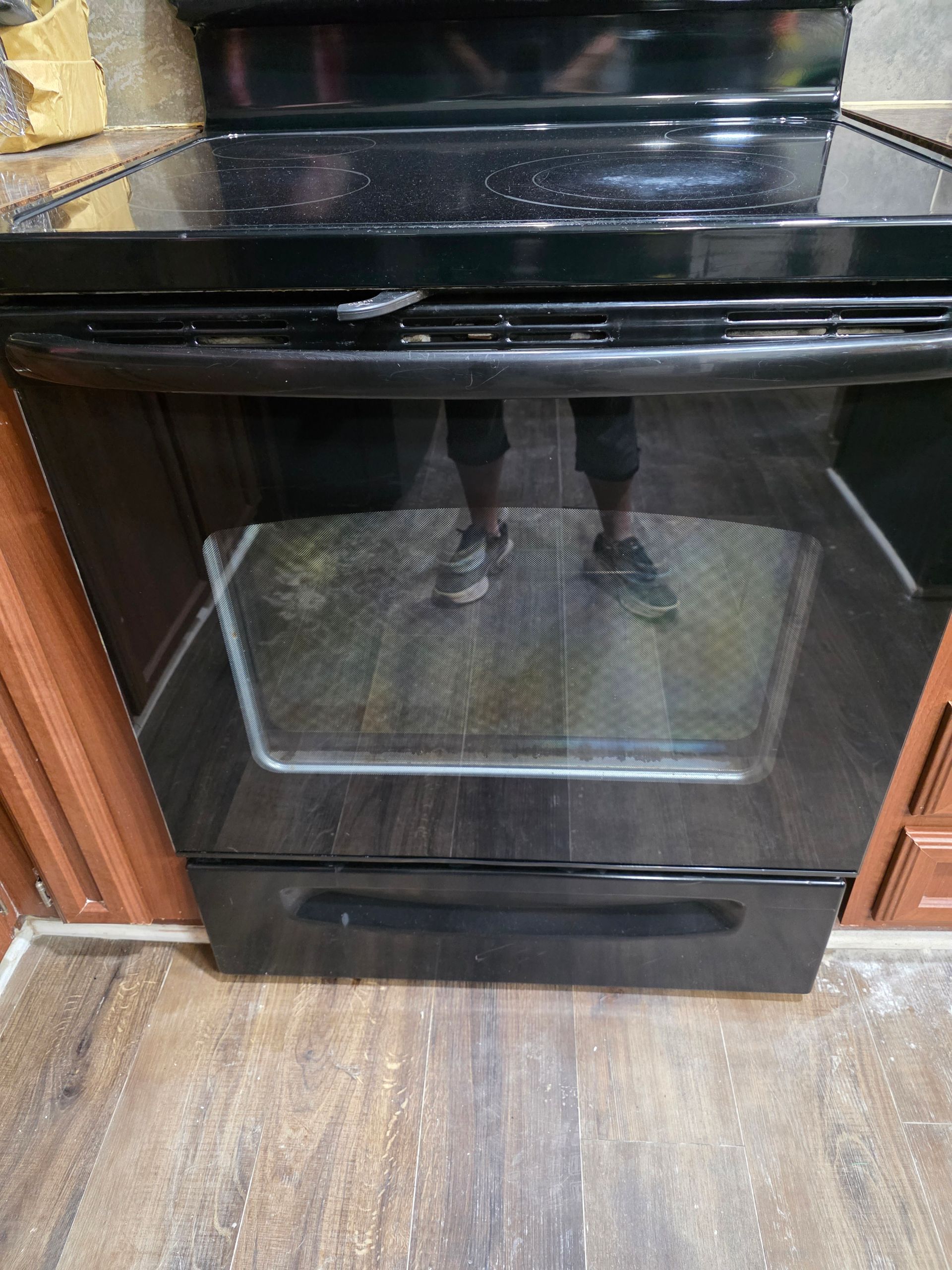 Black electric range with cooktop and oven door, in a kitchen.