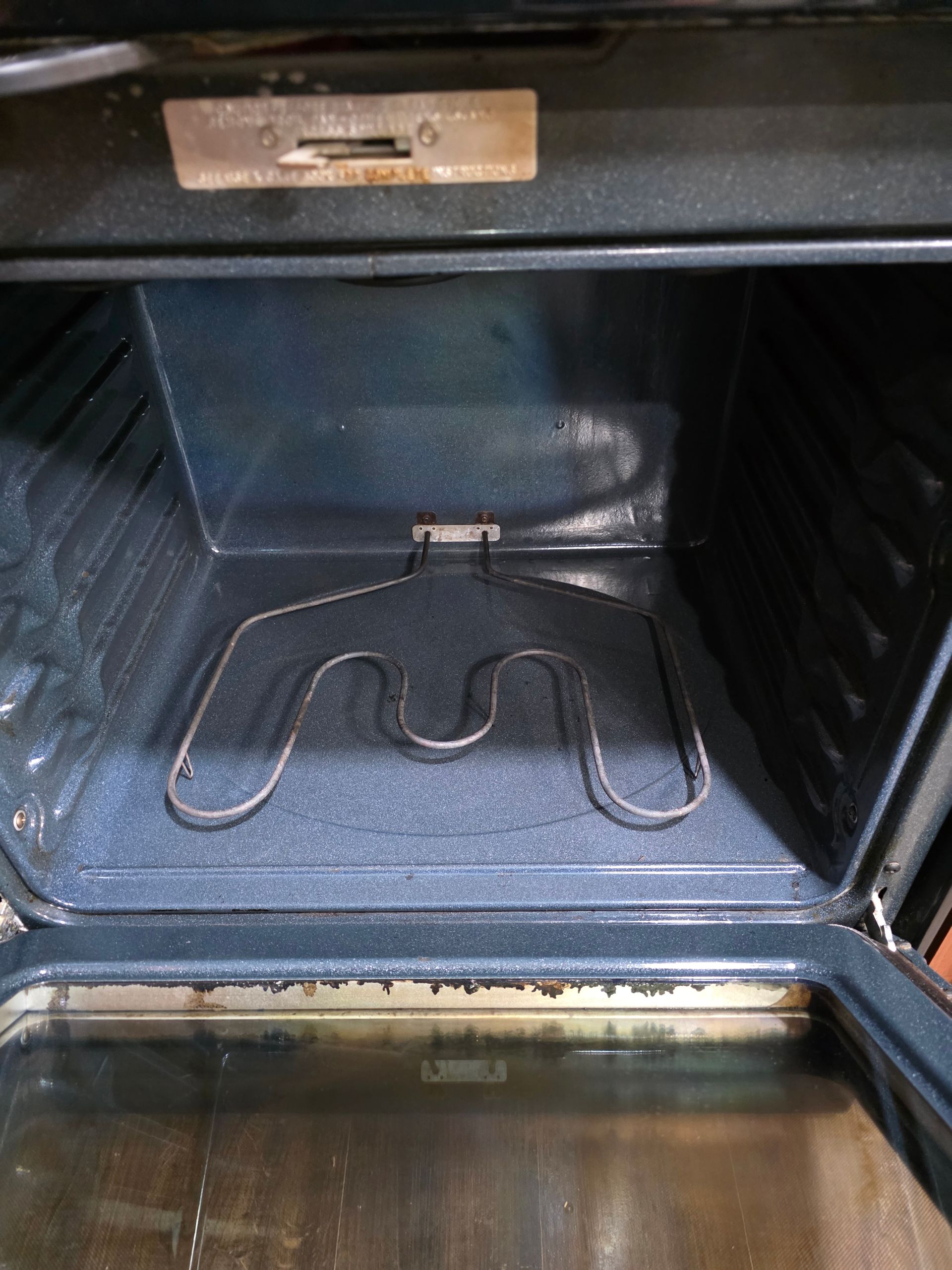 Opened oven interior with a heating element and blue walls.