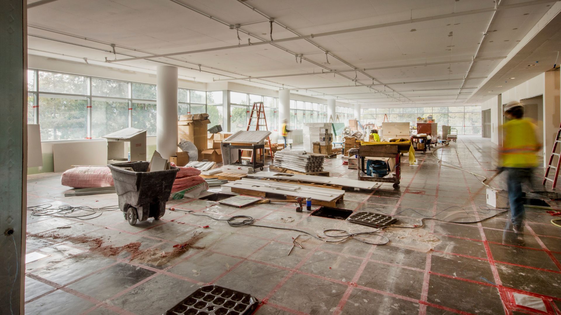 Interior of a construction site; debris, tools, and a worker in a vest.