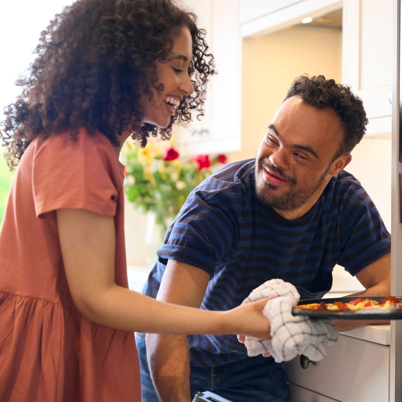 A man and a woman are smiling at each other in a kitchen