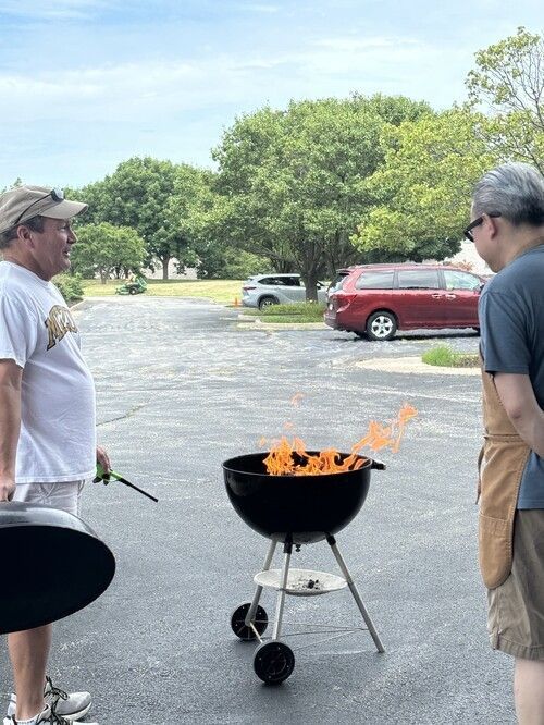 Two People at Fairview Church of Christ's Dumpster & Fire Event Starting a Grill