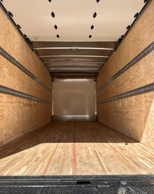Empty cargo truck interior with wood floor and walls.