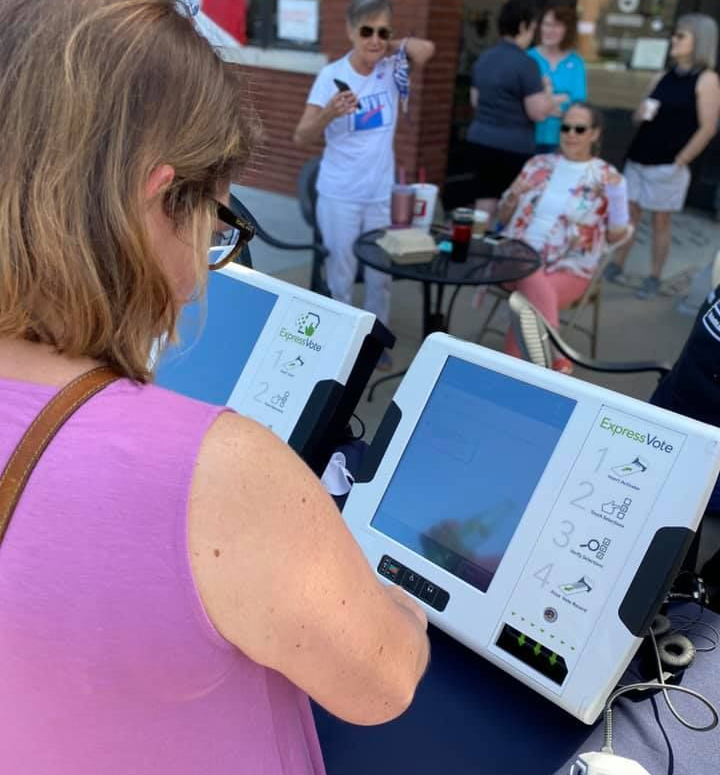 Maggie Ballard casting her vote on an electronic voting machine, participating in the election process.