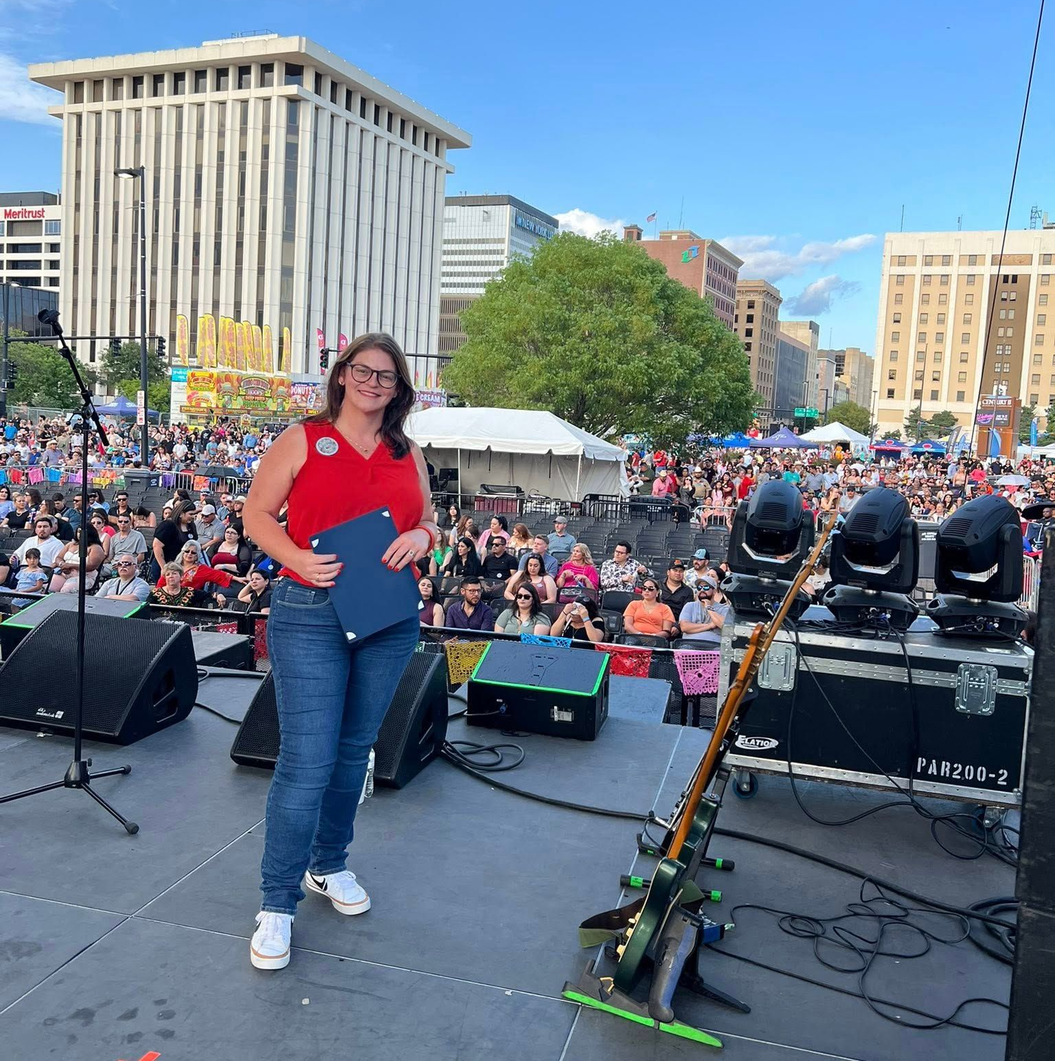 Maggie Ballard speaking on stage to a crowd, engaging with community members.