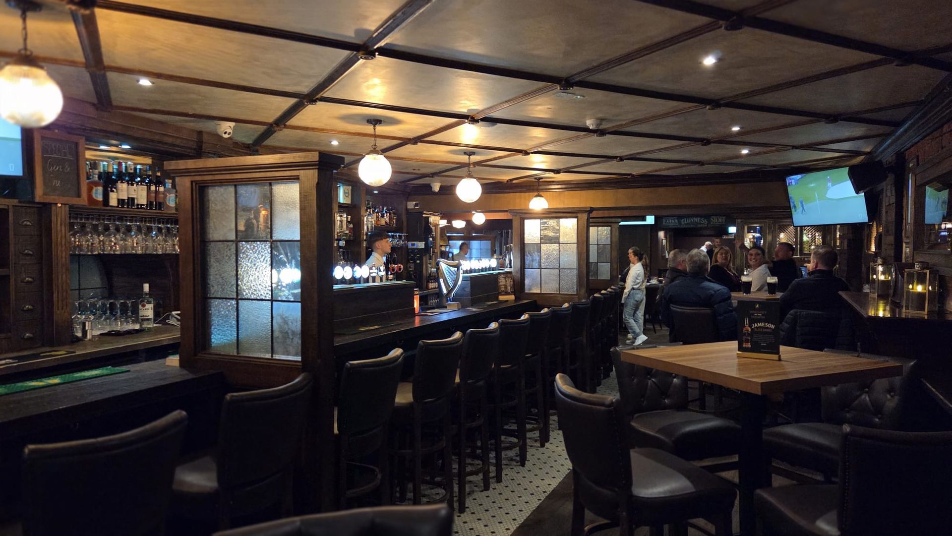 The wooden bar with brown bar stools, talking people and cosy atmosphere.