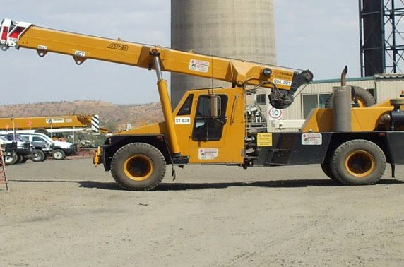 A yellow truck with a crane attached to it
