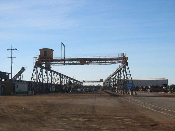 A large bridge over a dirt road with a blue sky in the background