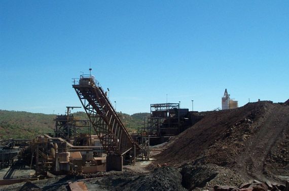 A large pile of dirt is sitting in front of a large machine.