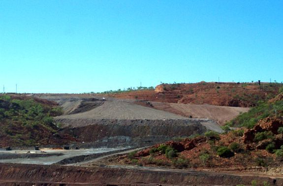 A large body of water surrounded by mountains and trees with a blue sky in the background.